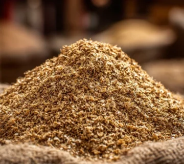نمای نزدیک از کنجاله تخت تخم پنبه وارداتی آذربایجان با بافت طبیعی و رنگ طلایی روشن روی کیسه کنفی