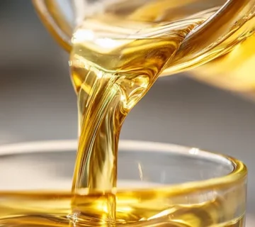 روغن سویا خوراک دام در حال ریختن در ظرف شیشه‌ای با نور طبیعی و رنگ طلایی شفاف